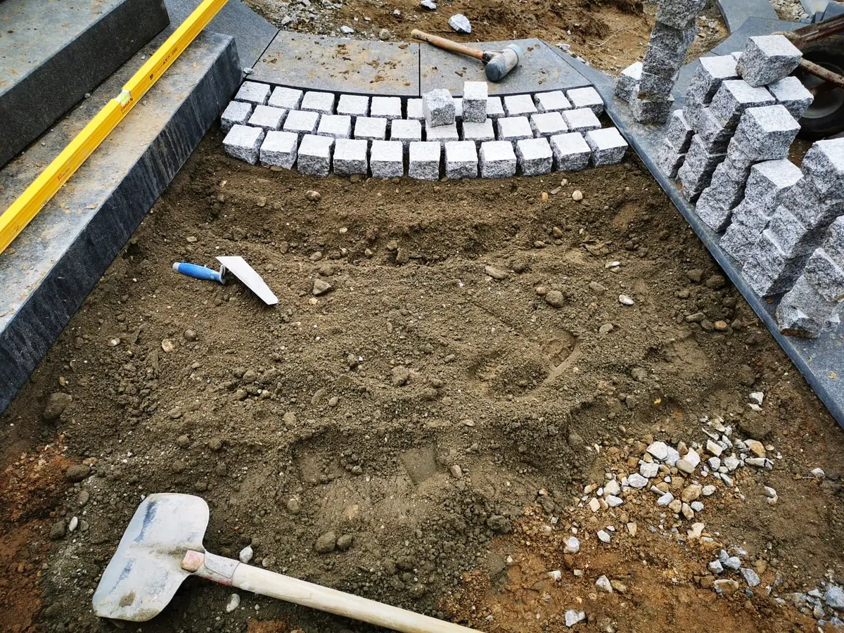 Vorbereitete Pflasterfläche mit Granitsteinen, Einfassung und Werkzeug