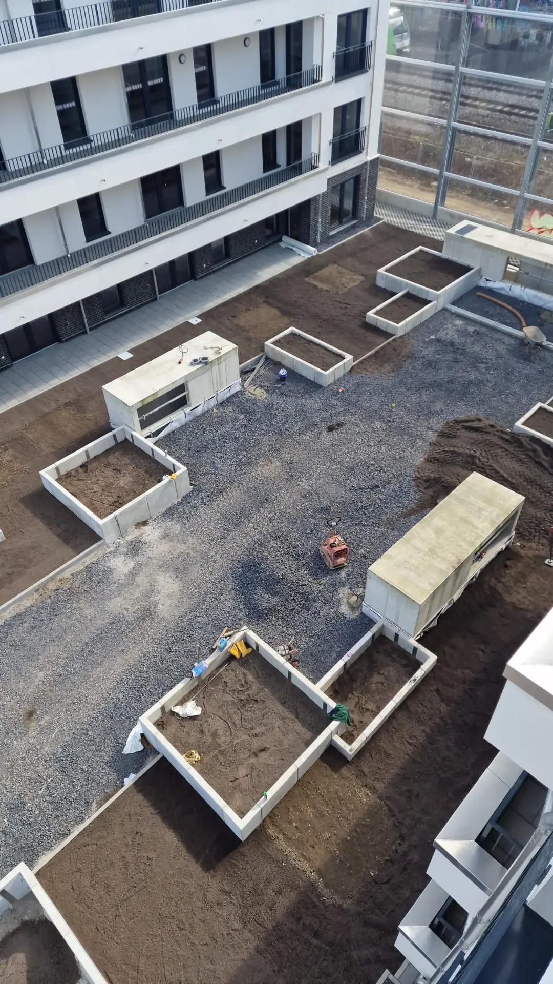 Innenhof einer Wohnanlage in der Bauphase mit Hochbeeten aus Betonelementen