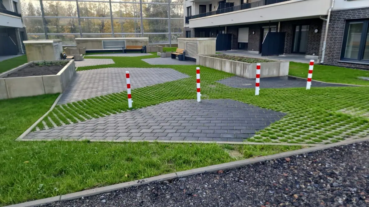 Fertig gestalteter Innenhof einer Wohnanlage mit Rasengittersteinen, Pflasterflächen, Hochbeeten und Sitzbänken