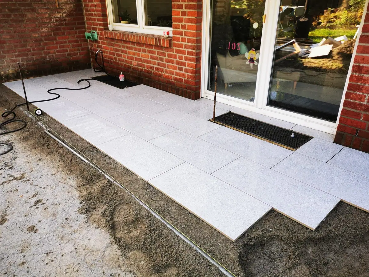 Verlegung heller Granitplatten für eine Terrasse vor der Terrassentür