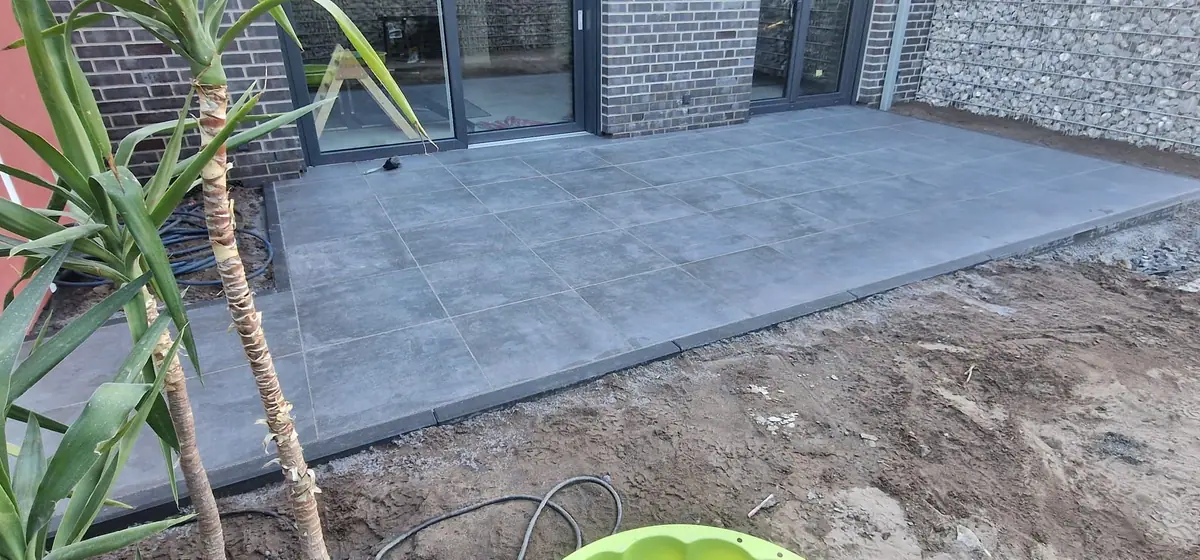 Neu verlegte Terrasse aus anthrazitfarbenen Großformatplatten an einem Neubau